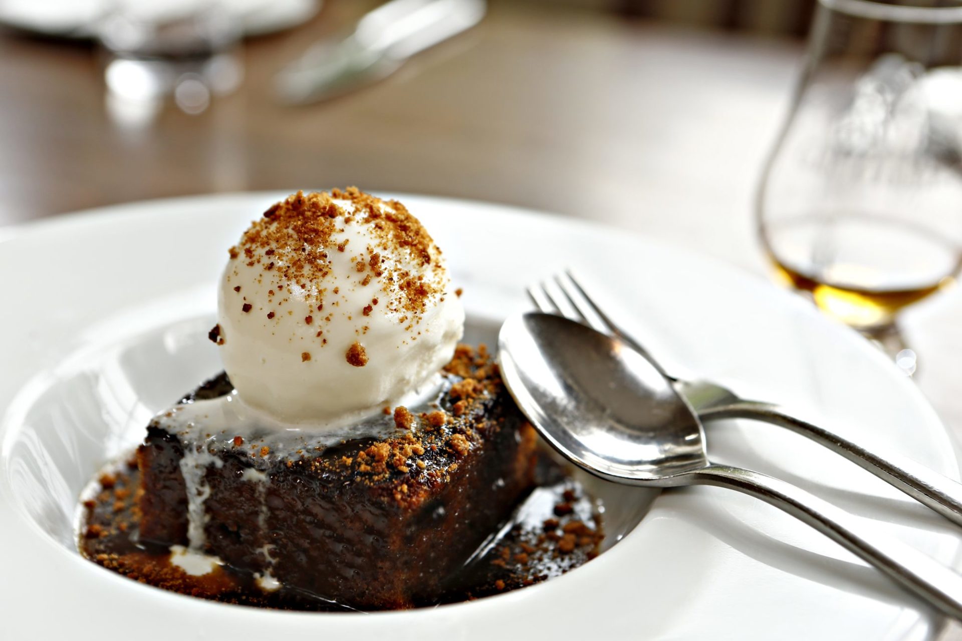 Sticky toffee pudding in bowl with ice cream on top